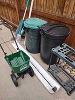 Overview showing two trash cans, spreader, gutter extensions, plant stand, mop
