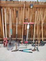 Full view of long-handled tools against fence