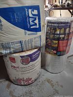 Fiberglass insulation rolls and reflective insulation roll standing together