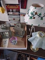 Group shot of all items including ceramic lamp, brass lamp, two lanterns, glass votive and sealed night-light pack