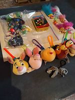 Group shot showing plush keychains, bagged Mario figures, Mickey puzzle tin, Trolls figures