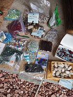 Overhead view showing assortment of glass gems, river rocks, mosaic tiles and decorative beads in bags, boxes and basket