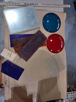 Mixed glass pieces laid out including clear round disc, colored round lenses, assorted rectangular panels