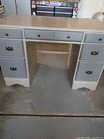 Front view showing seven drawers, two-tone paint, brass-tone hardware