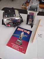 Blender base, container with lid, tamper and recipe book arranged on table