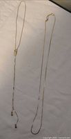 Two gold-tone chain necklaces laid flat