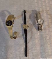 Three wristwatches: gold-tone Longines, black-strap Timex, silver-tone Ebel