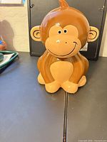 Front view of brown/tan ceramic monkey piggy bank