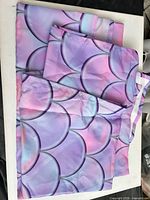 Folded pastel mermaid-scale polyester fabric panel on table
