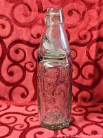 Full view of embossed aqua glass bottle with marble in neck