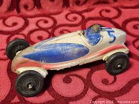 Full side view of antique rubber race car showing overall design and wear