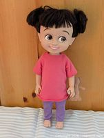 Full-length view of Boo doll standing against wood background