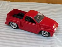 Driver side and front view of red die-cast lowrider pickup truck model