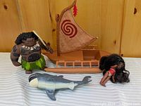 Group shot showing Maui figure, Moana doll, boat, shark