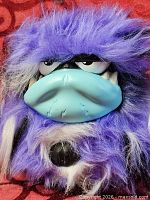 Front view of purple Grumblies plush showing fur, turquoise snout and eyes