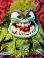Front view of green Grumblies plush monster showing face details and fur condition