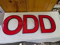 Front view of all three letters O D D on table