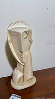 Front three-quarter view of plaster cubist lady head sculpture on wood surface