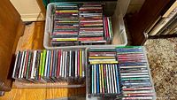 Two open clear bins filled with rows of Christmas CD jewel cases