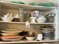Cupboard shelves with assorted dinnerware, bowls, plates, glasses