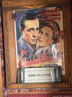 Movie poster mounted in wooden display with Now Playing sign below