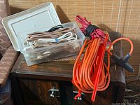 Overall view showing clear tote with multiple appliance cords, bundled red and green extension cords, and orange outdoor cord on reel