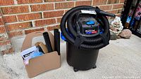 Mastervac shop vacuum with hose wrapped around lid, beige caddy of accessories beside unit