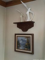 Ceramic bird sculptures displayed on wall shelf above framed painting