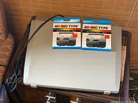 Closed typewriter with case lid, power cord, two sealed KO-REC-TYPE ribbon cartridges on top
