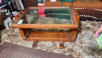 Full view of rectangular oak frame coffee table with glass top and lower shelf
