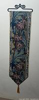 Full view of tapestry hanging from metal scroll hanger showing pattern and tassel
