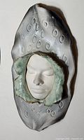Front view of ceramic wall mask showing face and textured surround