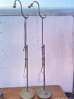 Full view of both brass floor lamps standing side by side showing overall form and height