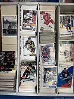 Three-row card storage box filled with hockey trading cards, visible examples from Upper Deck, Score, Pinnacle brands