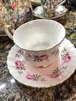 Teacup nested in saucer, rose pattern and gold trim visible