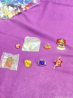 Group view of 8 enamel lapel pins on purple fabric