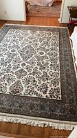 Full view of ivory, blue and brown Persian style area rug with fringe