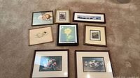 Eight framed prints laid out on carpet