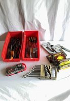 Full lot view: red bins with pliers and screwdrivers, wrench set, staplers, staple boxes, Husky kit