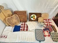Cutting boards, linens, potholders displayed on table