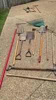 Full lot laid out showing mix of long-handled tools and cutting tools