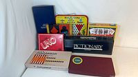 Group of boxed board games including UNO, Pictionary, Scrabble, Hop Ching, Backgammon, unidentified blue box