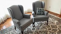 Front view of both grey wingback chairs with pillow