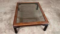 Full view of table angled showing frame, glass top, and legs
