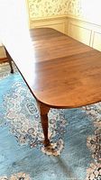 Full length view of walnut dining table showing rounded end and turned leg