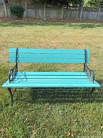 Front view of turquoise slatted bench on lawn