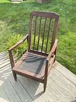 Front view of mission-style wooden rocking armchair showing slat back, arms, seat frame