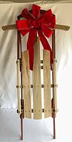 Front view of vintage wooden sled with red bow