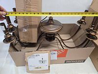 Chandelier frame with six arms in box, tape measure showing width