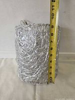 Cylindrical brushed steel wire shade with tape measure showing ~10 in. height